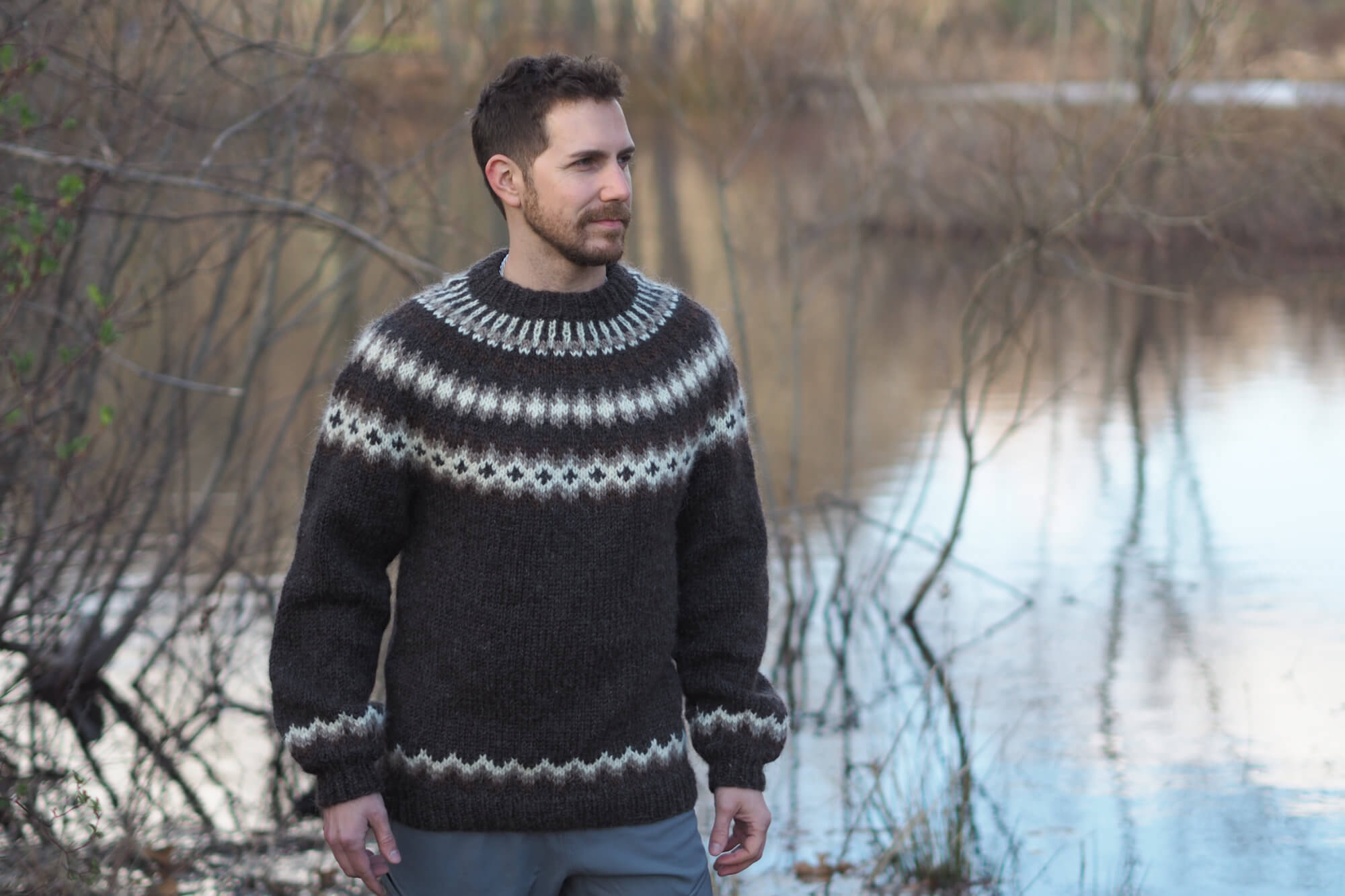 man wearing Turf and Clouds Lopi sweater outside near pond